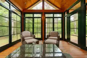 Porch Conversions featuring rustic wood accents, large retractable windows, and cozy wicker seating.