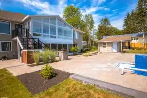 Insulated Sunroom with large glass windows and sliding doors overlooking a landscaped patio.