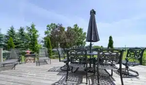 A spacious outdoor patio with glass railings, featuring outdoor seating and lush landscaping.