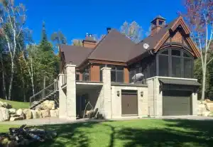 A luxurious stone and wood home featuring a topless glass railing on the balcony, offering unobstructed scenic views.