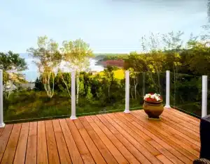 A spacious outdoor patio with glass railings, featuring outdoor seating and lush landscaping.