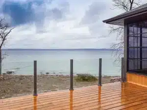 Cedar-Finished Aluminum Decking with Topless Glass Railing Overlooking a Forested Landscape