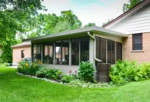 Insulated Sunroom with large screened windows attached to a brick home.