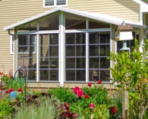 Sunspace WeatherMaster™ Model 200 sunroom attached to a manufactured home, featuring vertical sliding windows and a white aluminum frame.