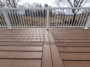 A close-up view of a Trex composite deck with rich wood tones, sturdy white railing, and a scenic outdoor backdrop