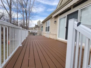 A spacious Trex composite deck with rich brown tones, white railing, and a stylish home exterior in the background.