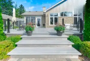 A modern home with a stylish AlumaDeck decking system, featuring a combination of stone and siding exterior, large white-framed windows, and sleek black aluminum posts for a contemporary outdoor space.