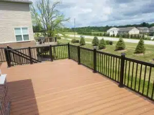Black aluminum picket railing installed on a spacious wooden deck with a scenic backyard view.