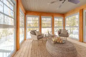 WeatherMaster™ Windows in a cozy sunroom with large clear panels, offering a bright, airy space with a scenic outdoor view