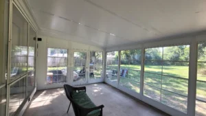 Interior view of a WeatherMaster™ sunroom Model 200 featuring large glass panel windows with a classic grid design, allowing natural light and a scenic backyard view