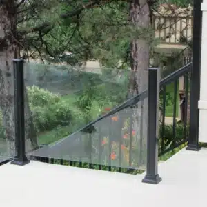 Topless glass railing on an outdoor deck, featuring black metal posts with a scenic view of green grass, trees, and a flowing river in the background