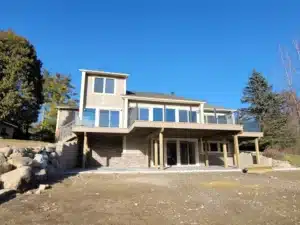 A stunning house with a spacious balcony featuring topless glass railing, offering a clear view of the outdoors with a bright blue sky in the background