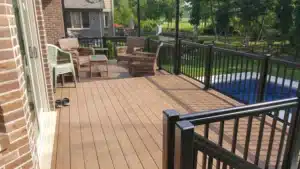 Trex Composite Decking installed on a spacious outdoor deck with black metal railings, wicker furniture, and a poolside view